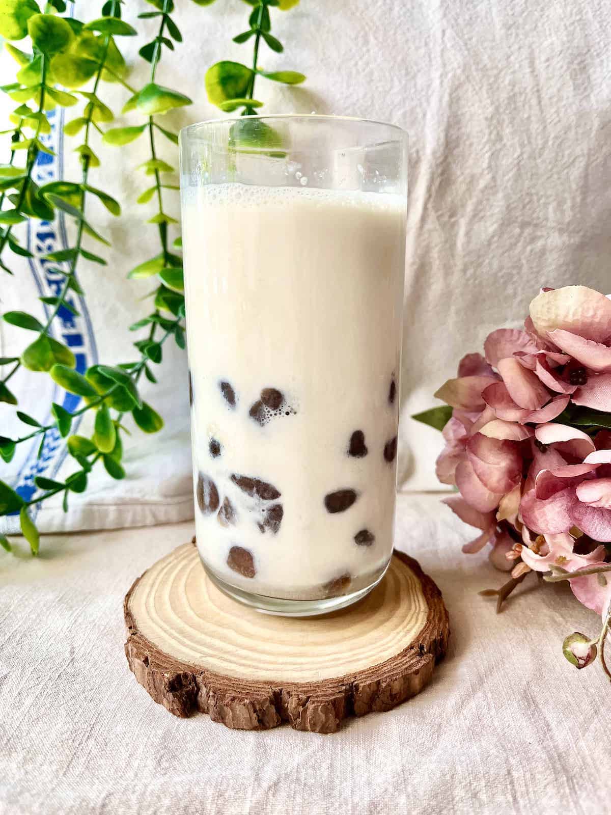 A tall glass of jasmine milk tea with boba pearls.