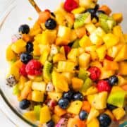 A mix of tropical fruits in a glass bowl.