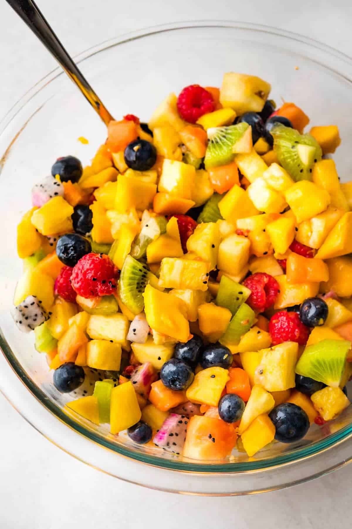 A mix of tropical fruits in a glass bowl.