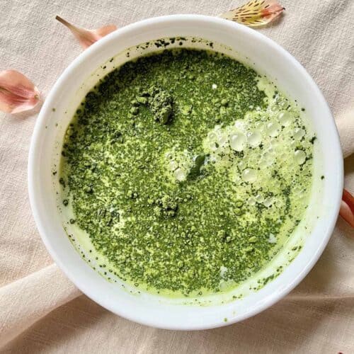 Matcha powder and whole milk in a white bowl.