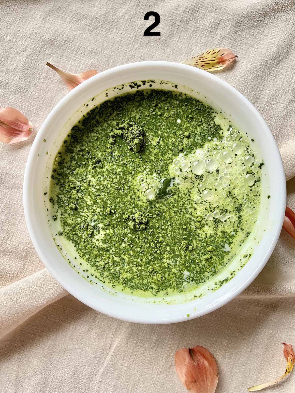 Matcha powder and whole milk in a white bowl.