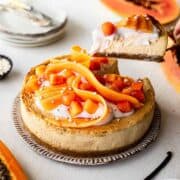 A beautiful cheesecake with sliced and cubed papaya on top.