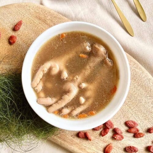 A bowl of Chinese chicken feet soup with peanuts and goji berries.