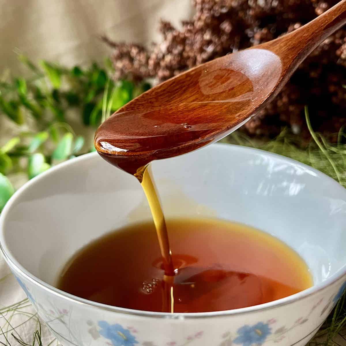 Close-up of someone scooping up homemade maple syrup from a white bowl.