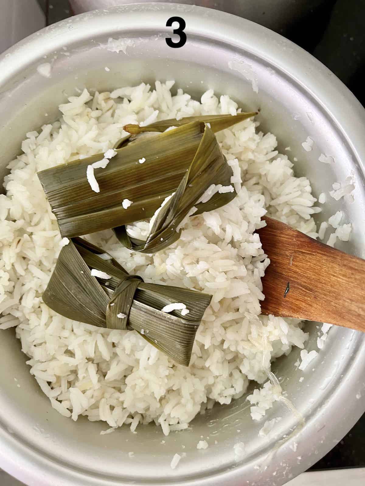 Using a wooden spatula to fluff rice.