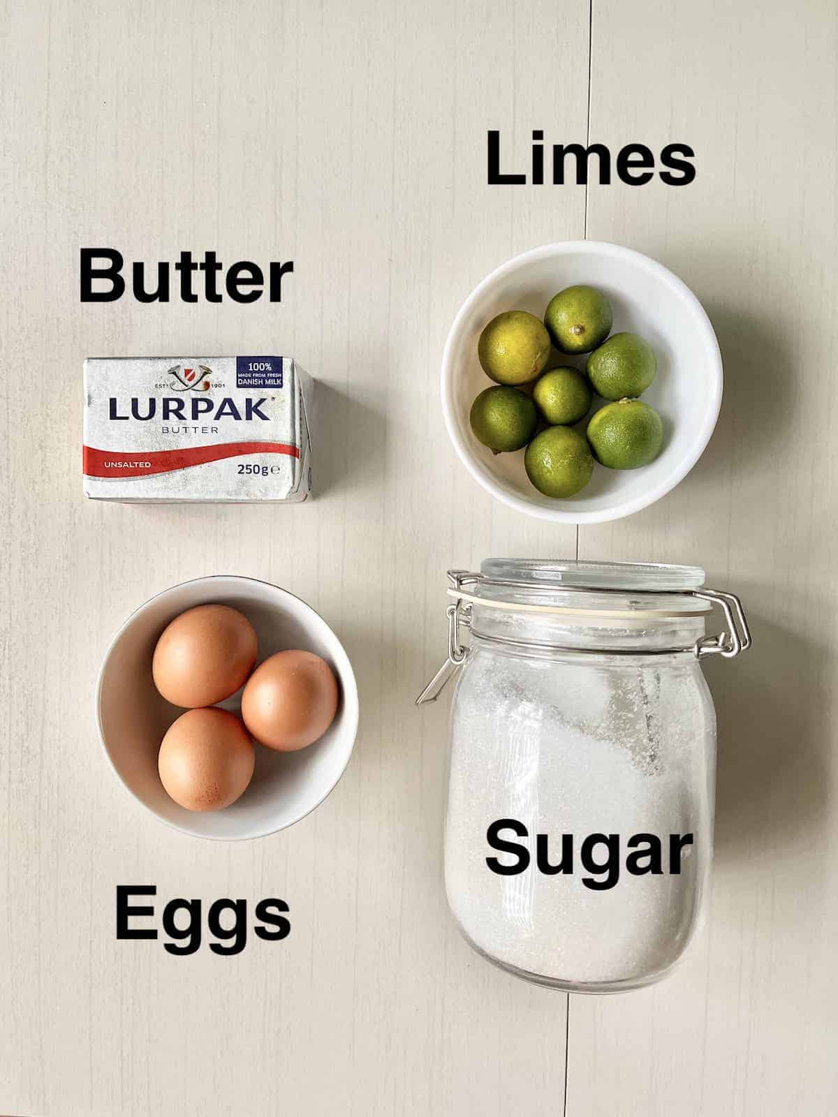 The 4 ingredients needed to make lime curd on a cream background.