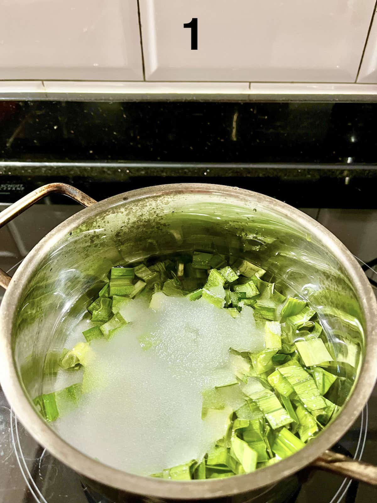 Pandan leaves, water and sugar simmering in a pot.