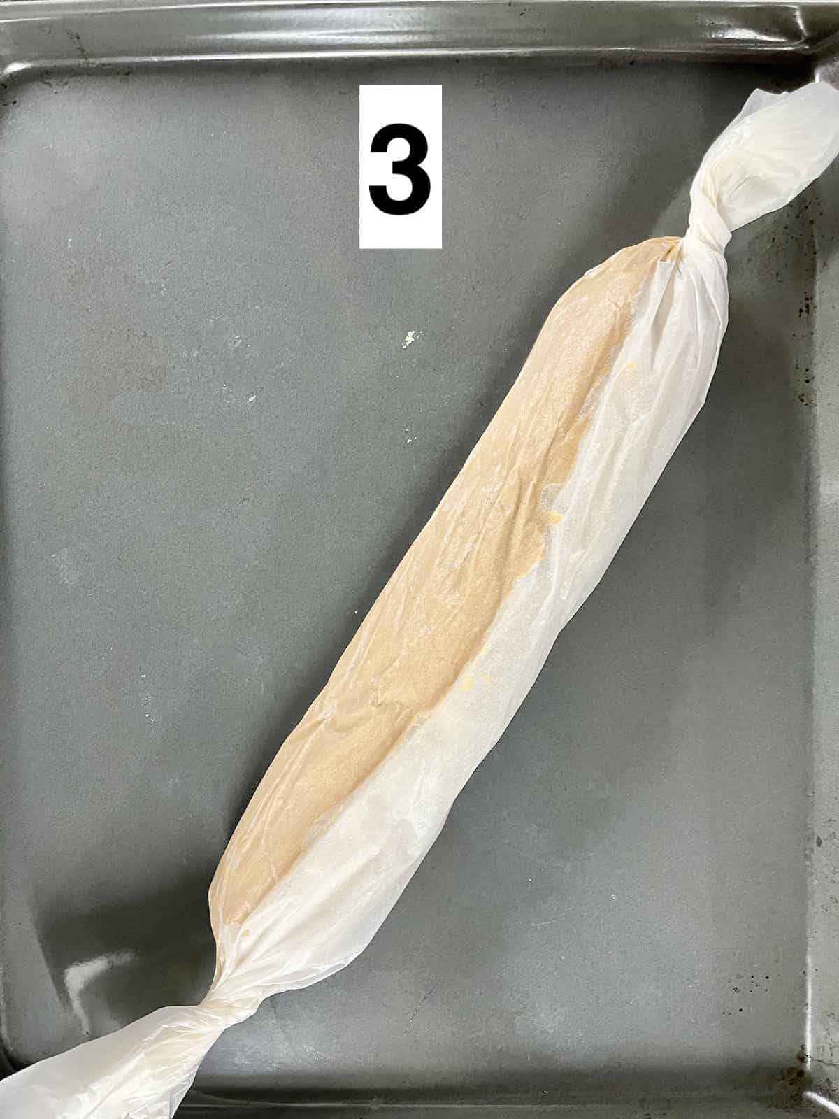 A log of brown sugar cookie dough wrapped in parchment paper.