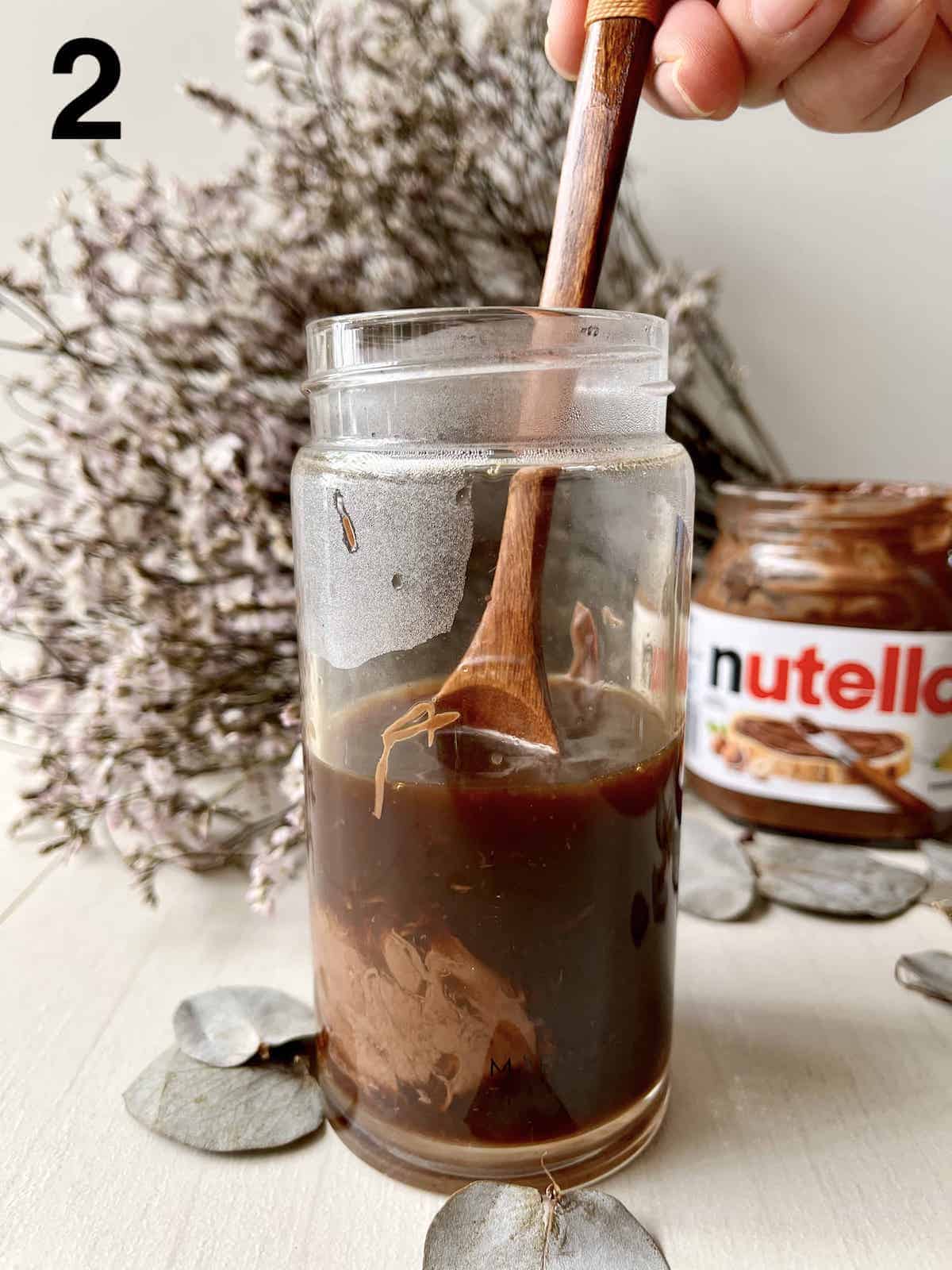 Stirring a tablespoon of nutella hazelnut spread into coffee.