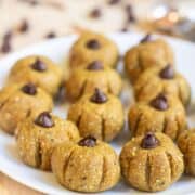 A white plate full of little pumpkins made from cashew.