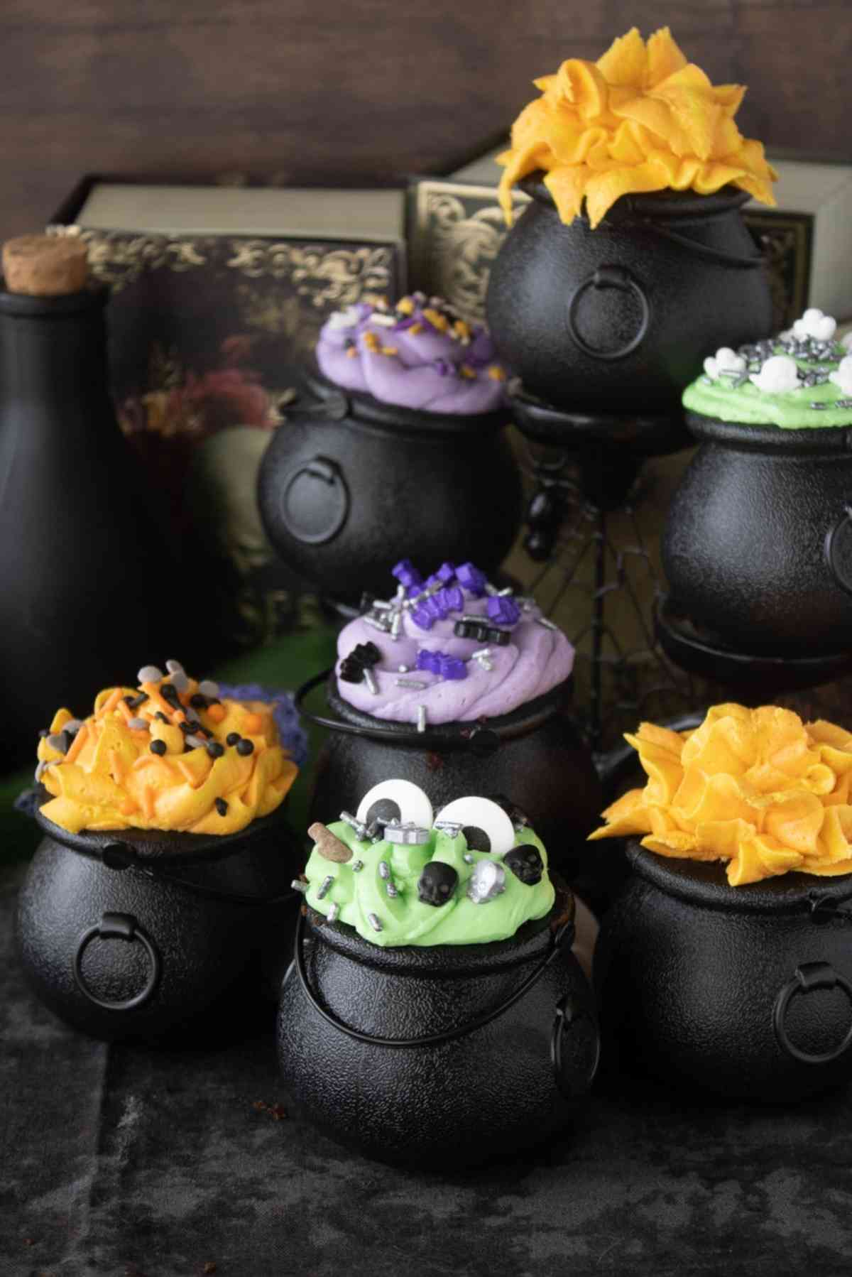 7 mini cauldron cakes which are green, orange and purple in color.