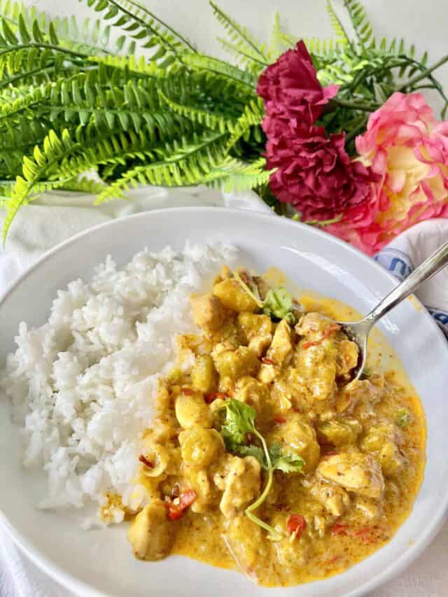 Someone scooping up thick pumpkin chicken curry with white rice.