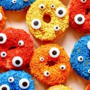 Blue, yellow, orange and red sprinkled donuts next to each other.