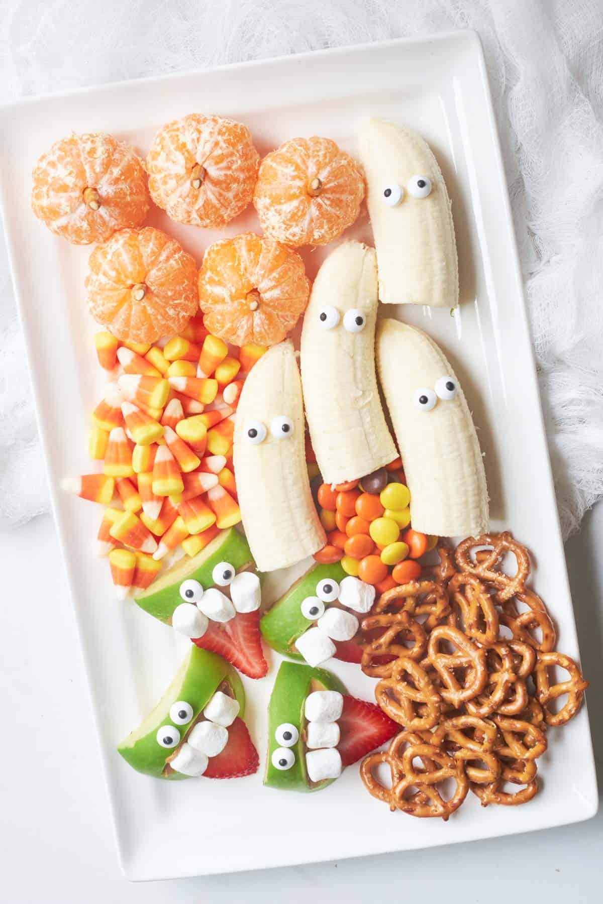 A healthy Halloween fruit platter with bananas and pretzels.