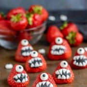 Several strawberries decorated with fondant into Monster-shaped desserts.