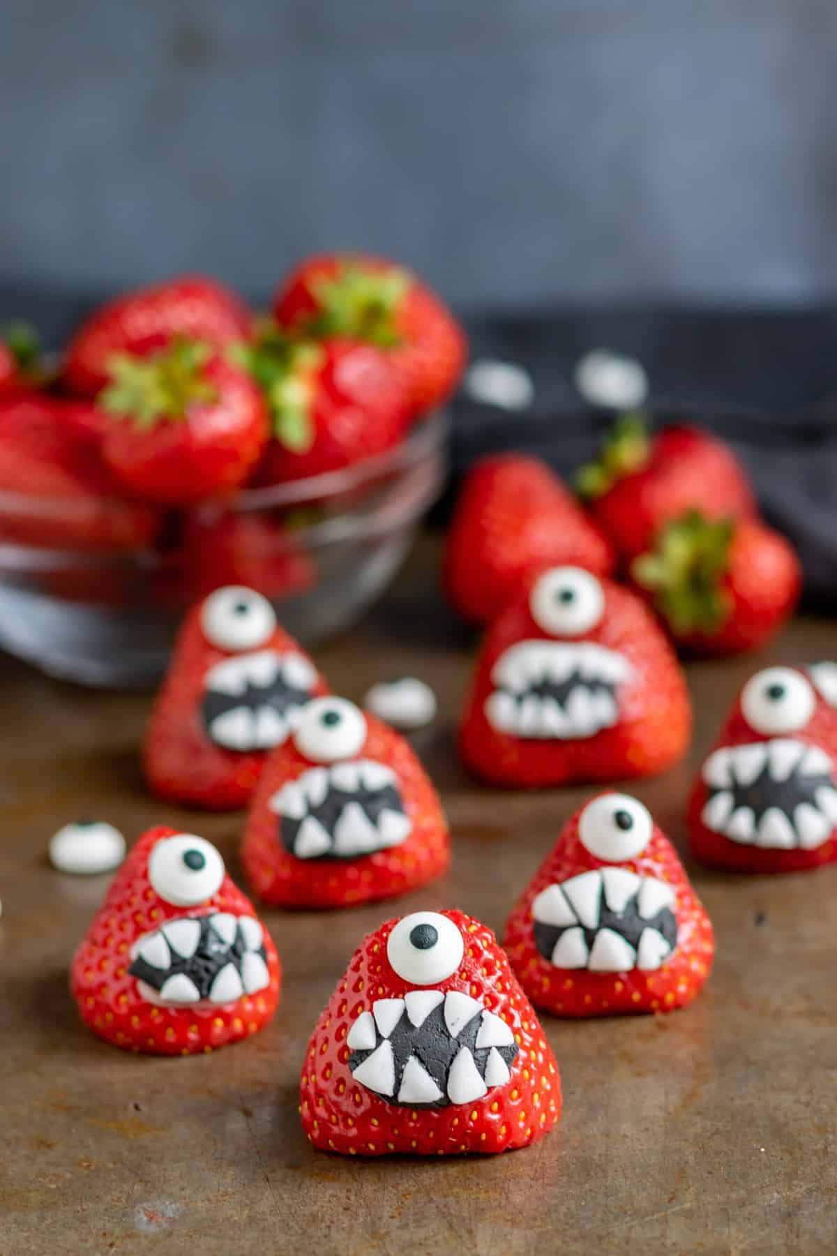 Several strawberries decorated with fondant into Monster-shaped desserts.
