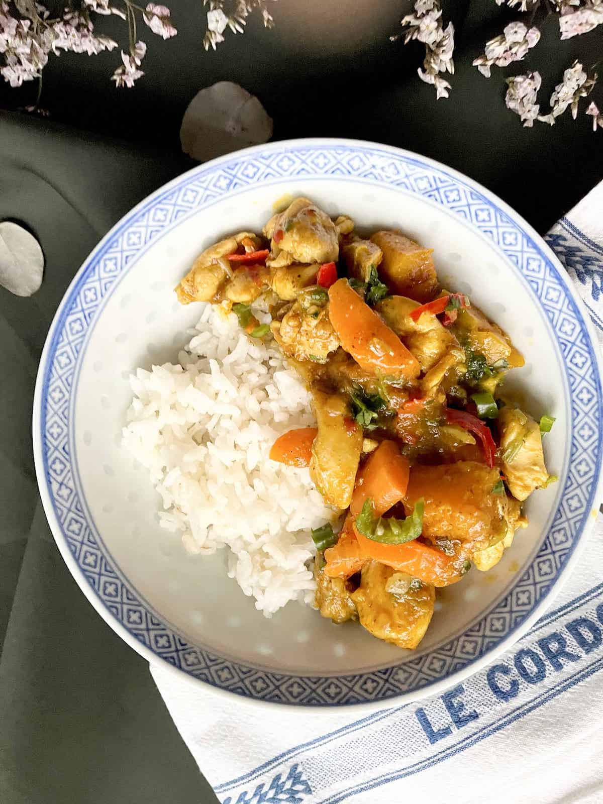 A plate of pumpkin chicken curry with carrots and white rice.