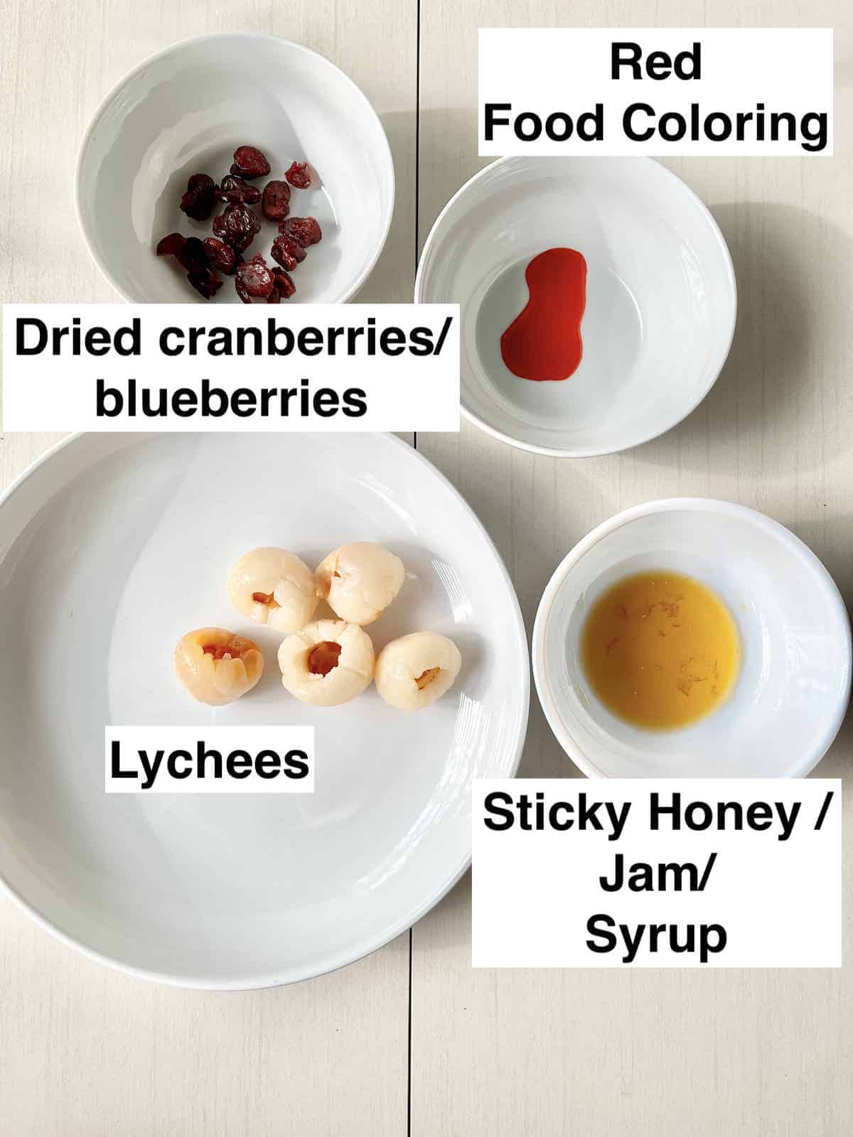 Lychees next to maple syrup, red food coloring and a bowl of dried cranberries.
