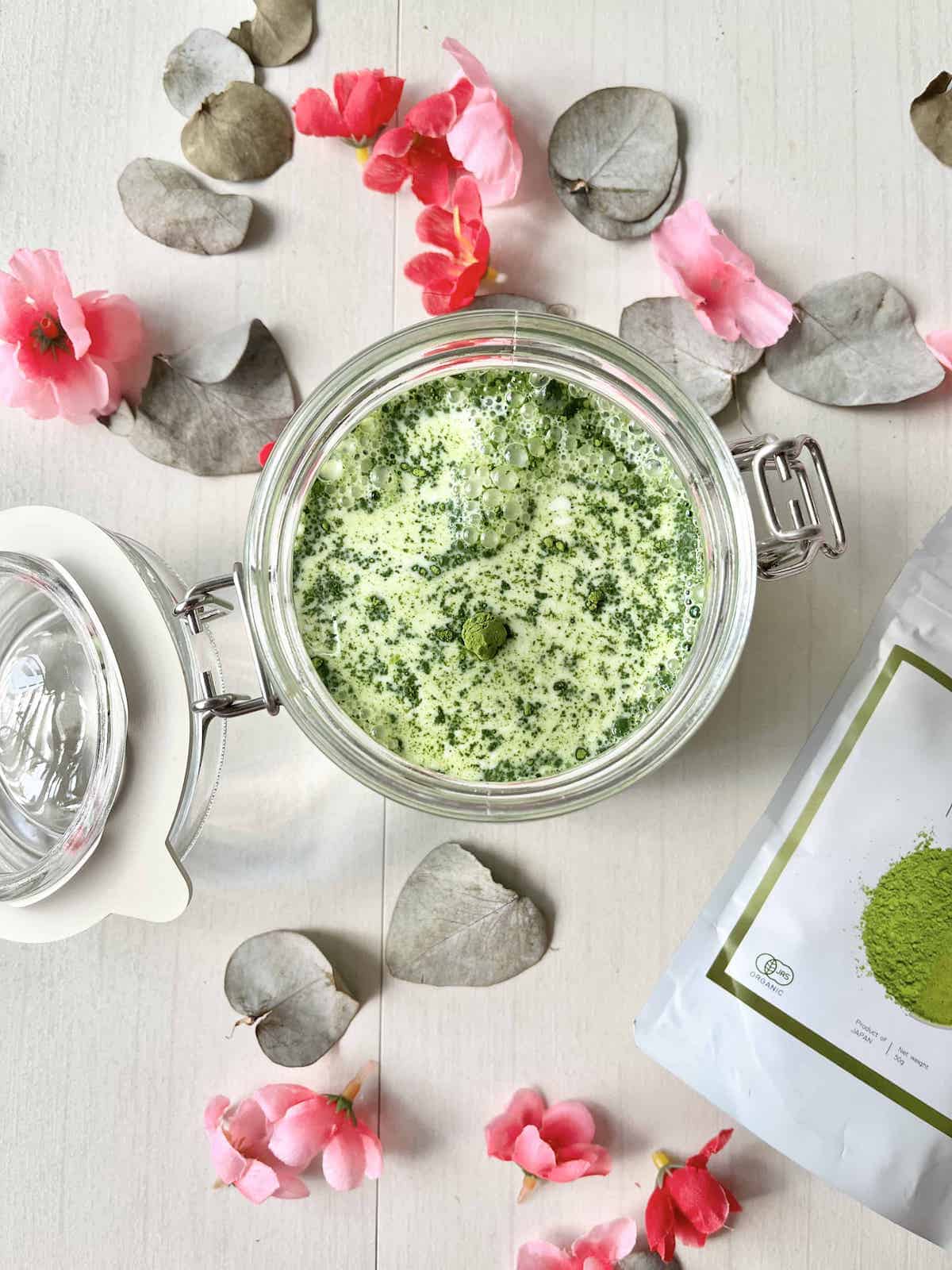 Matcha powder on oat milk in a mason jar.