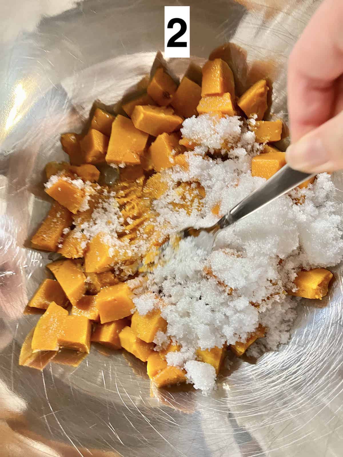 Mashing sugar into steamed pumpkin cubes.