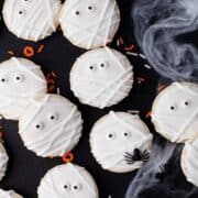 Lots of white mummy sugar cookies on a black background.