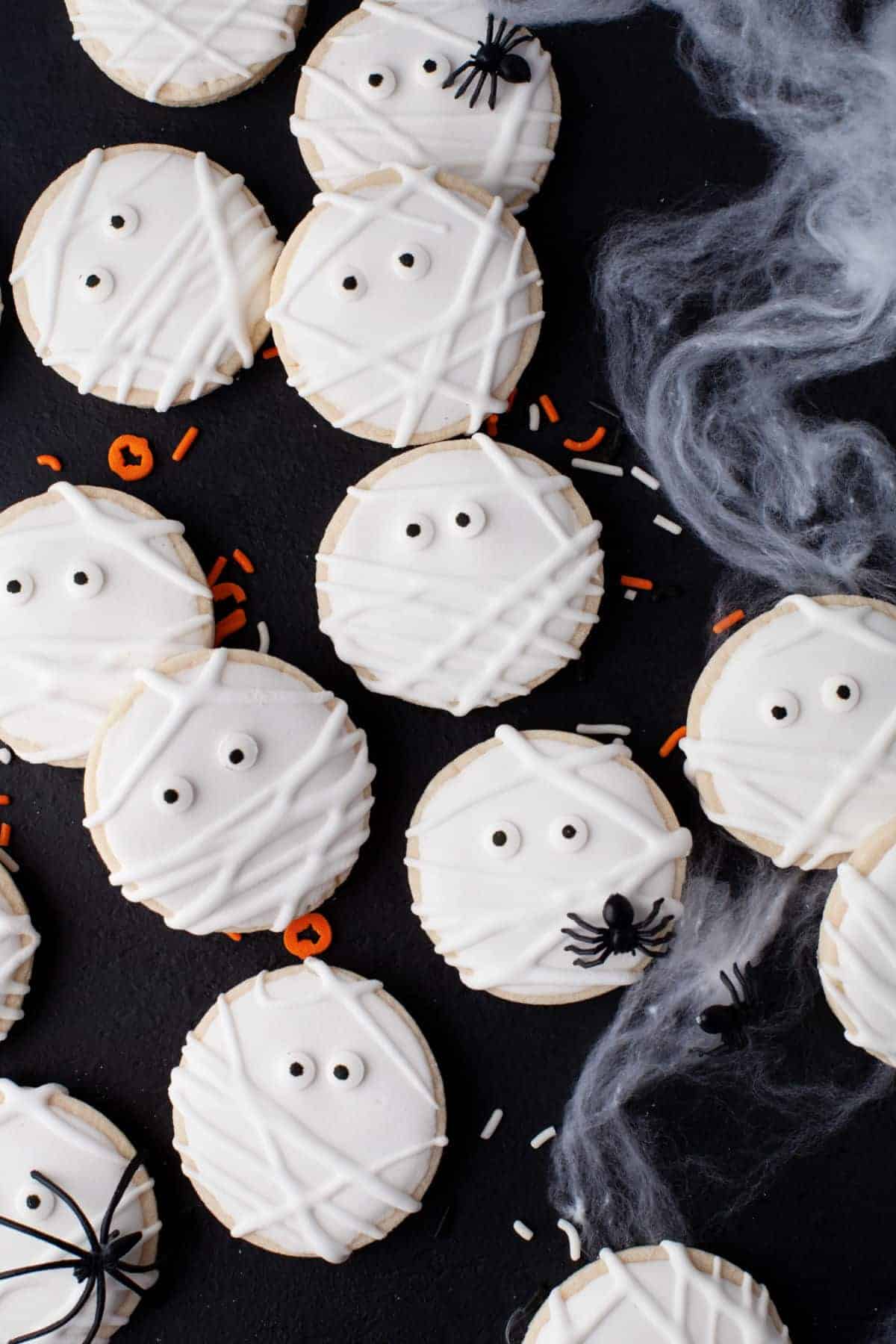 Lots of white mummy sugar cookies on a black background.