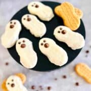 Ghost shaped white cookies on a black plate.