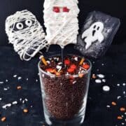 3 rice krispies decorated as ghosts on sticks.