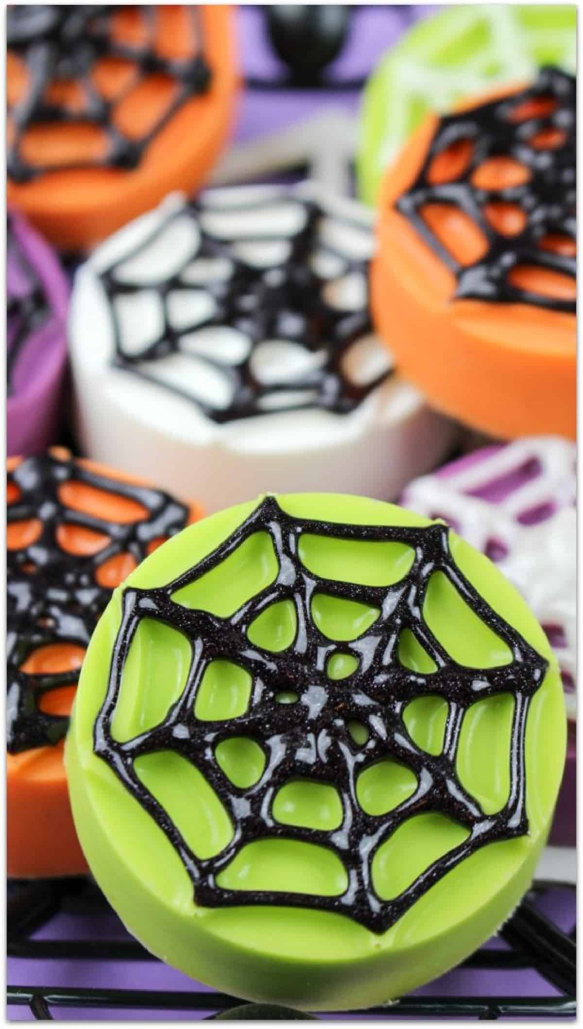 Close-up of a green cookie covered in a black edible spiderweb.