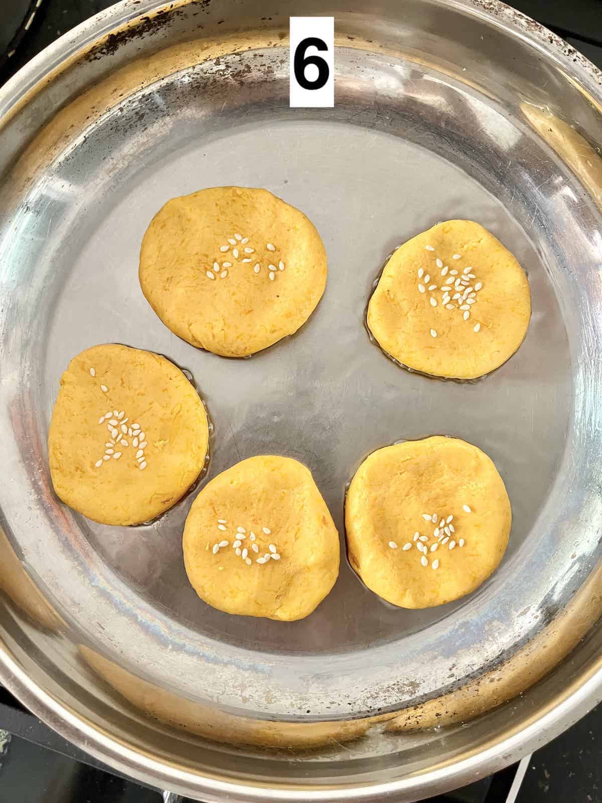 5 pumpkin pancakes being shallow-fried in a saucepan.