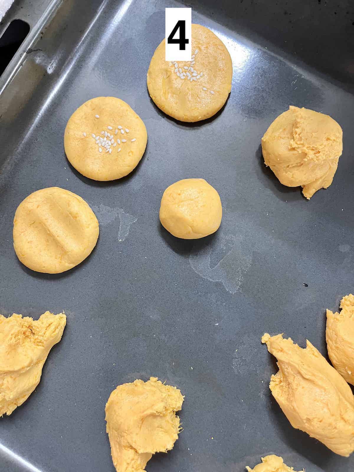 A tray with pumpkin dough balls and flattened pumpkin pancakes.