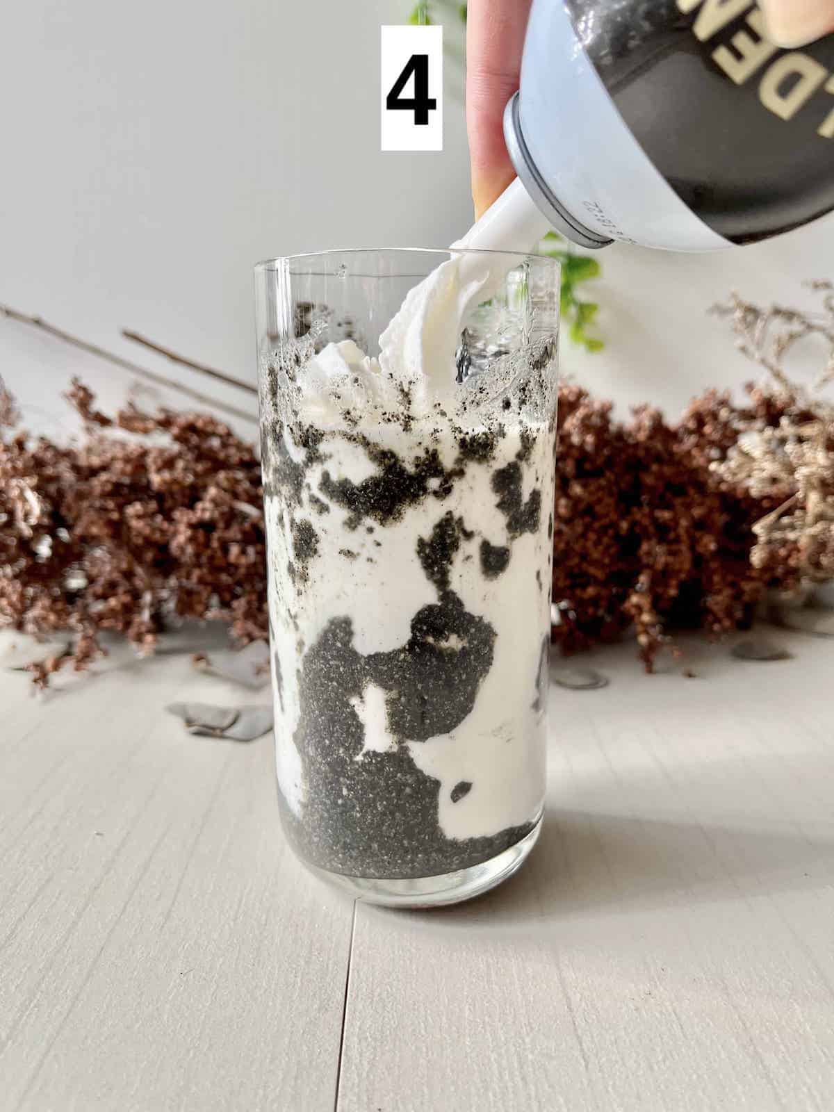 Spritzing sweet whipped cream on a black and white latte.