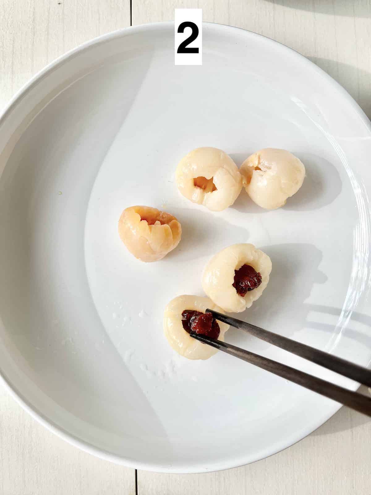 Stuffing dried cranberries into the hole of a lychee fruit.