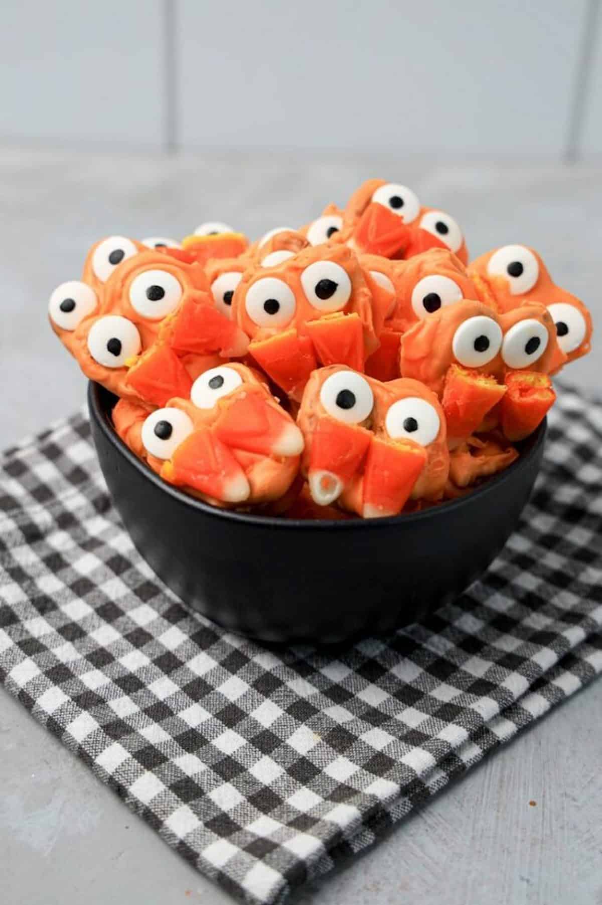 Red vampire fang decorated pretzels huddled together in a black bowl.