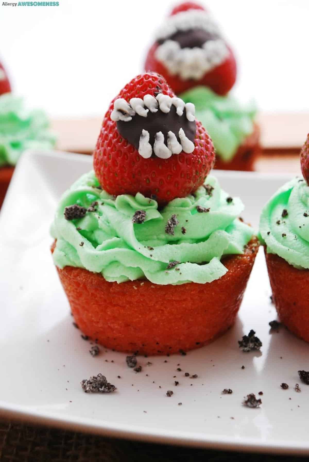 Close-up of a strawberry on green frosting cupcake that looks like a Venus Fly Trap.