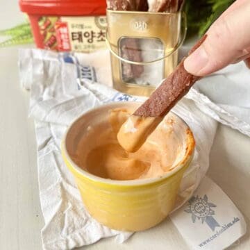 Close-up of someone dipping a SPAM fry into Gochujang Aioli.