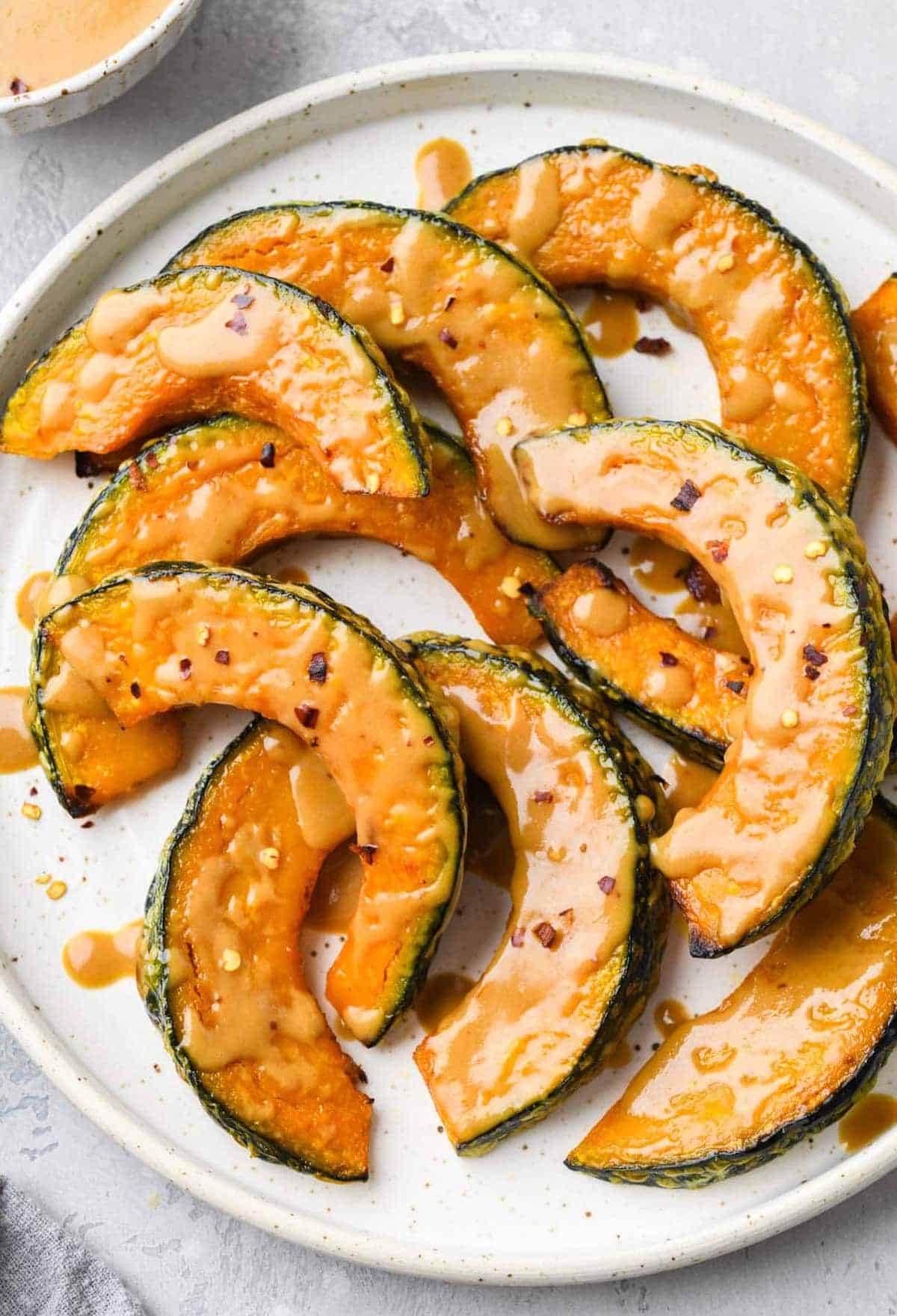 Sliced Kabocha Squash glazed with miso on a white plate.