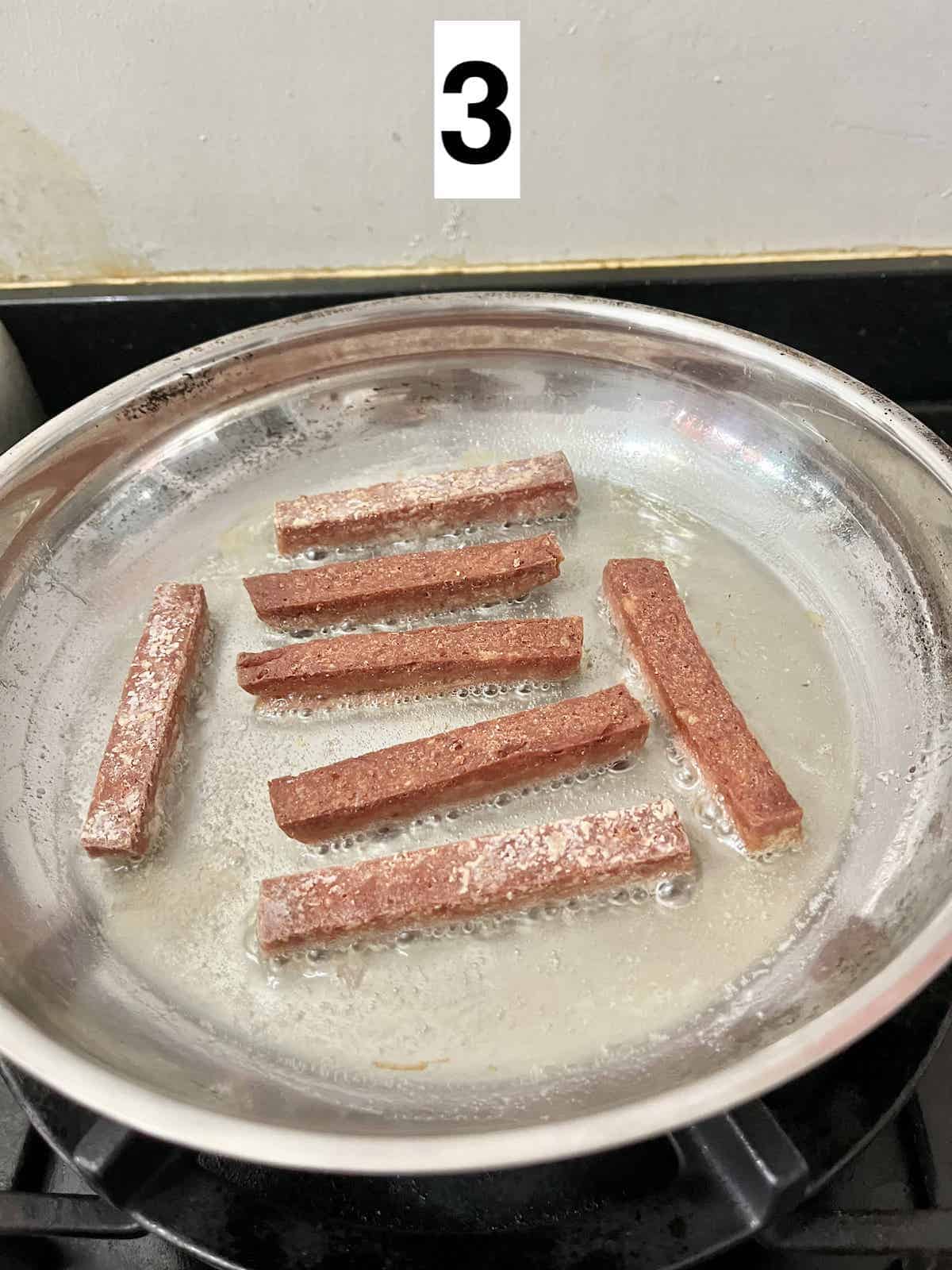 SPAM fries being fried in a shallow layer of oil.