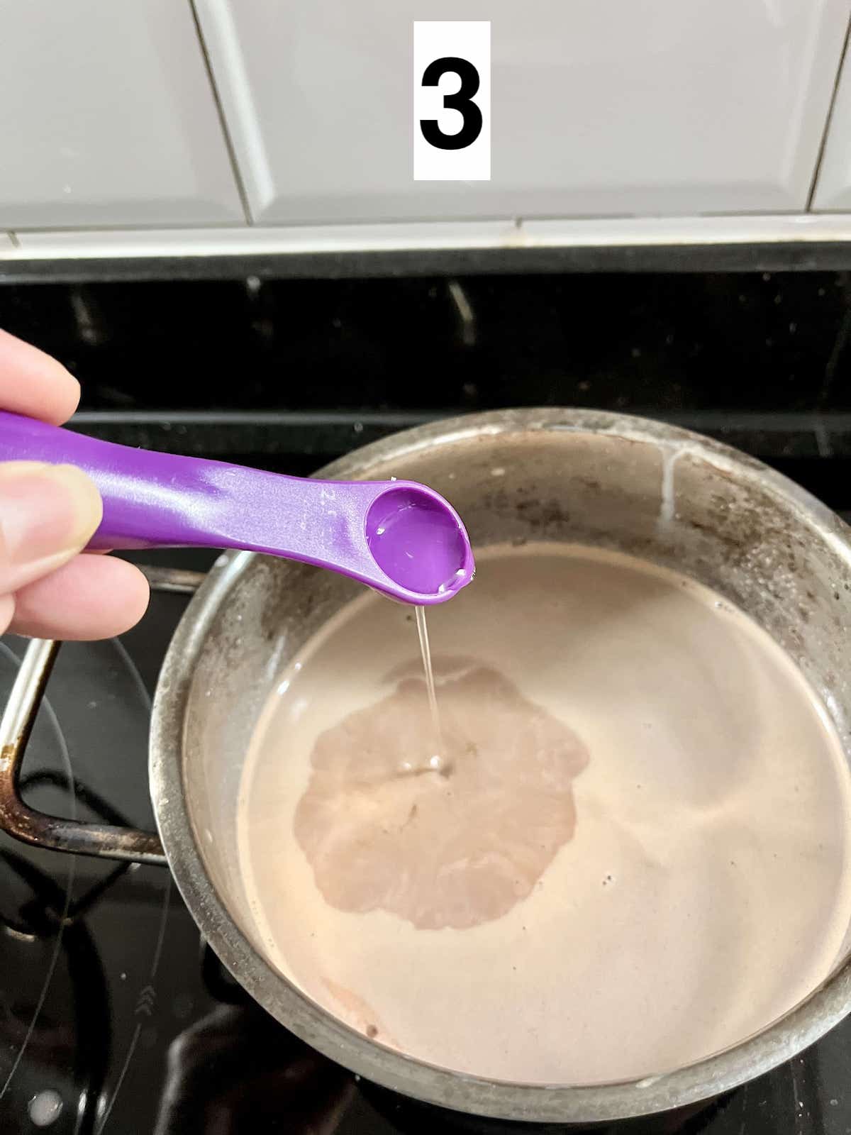 Adding peppermint flavor to a pot of hot chocolate.