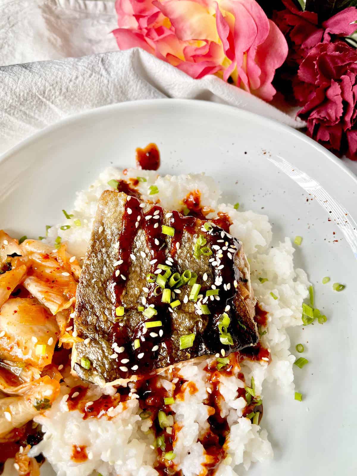 Close-up of a crispy skin salmon topped with Korean gochujang glaze.