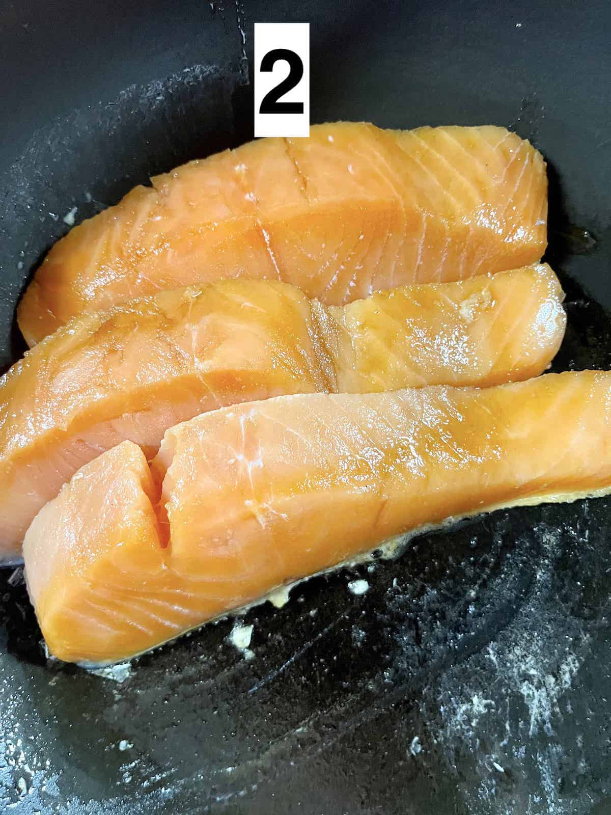 3 salmon filets skin-side down in a pan.
