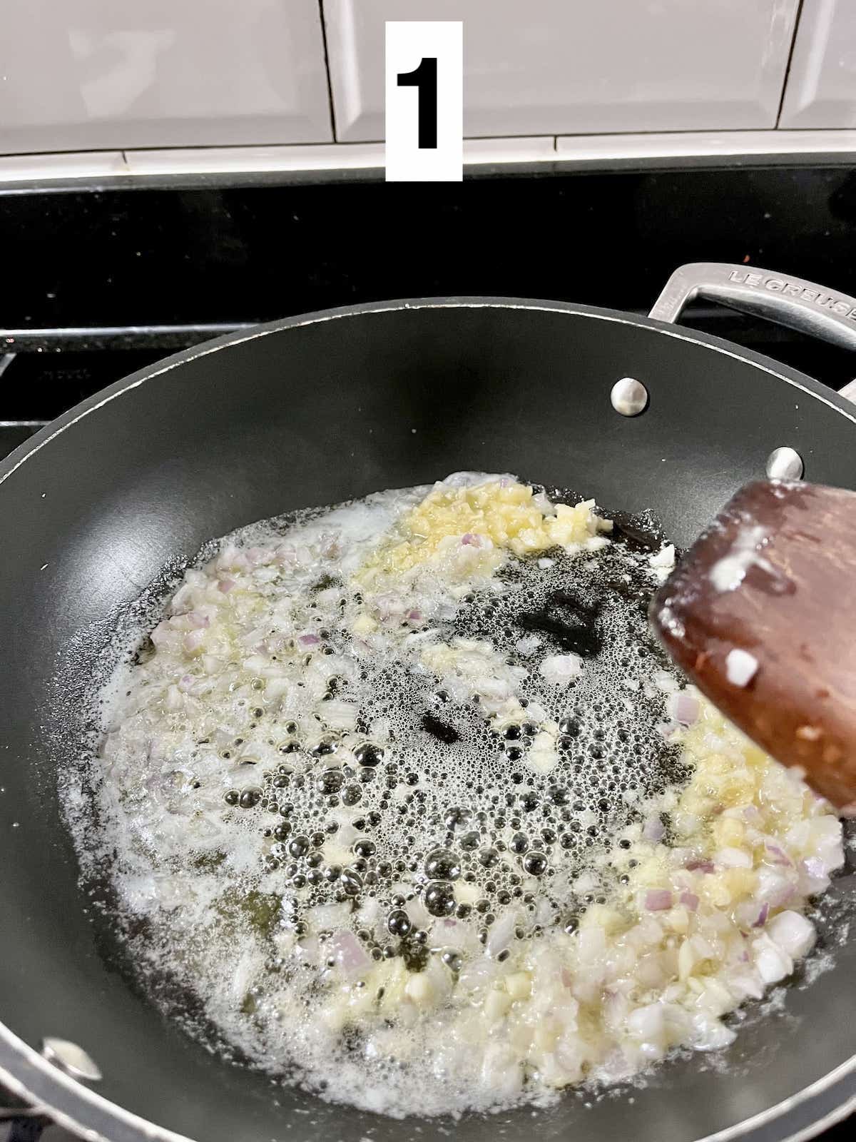 Minced onions and garlic being sautéed in butter.