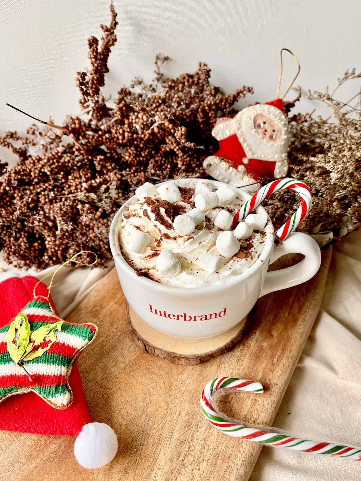 A mug of Starbucks-inspired peppermint hot chocolate with Christmas decorations around.