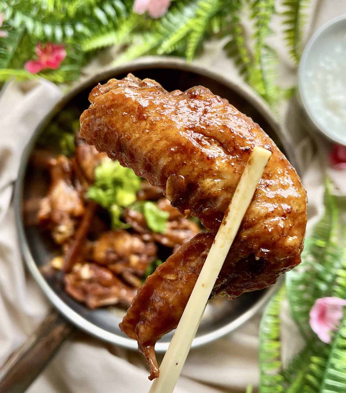 A close-up of a glistening, brown, sticky chicken wingette.