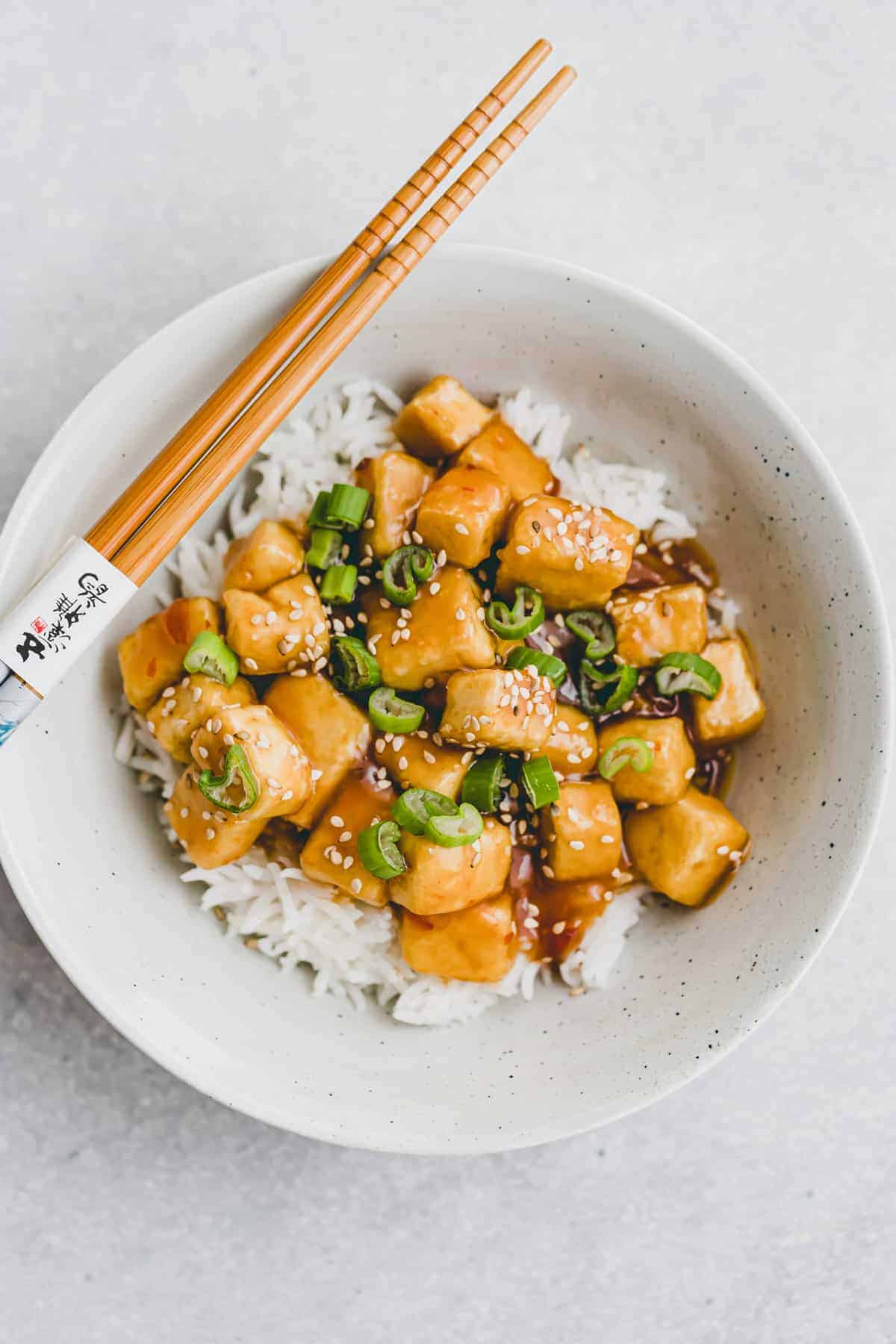 Tofu Cubes on white rice in a neutral coloured bowl.