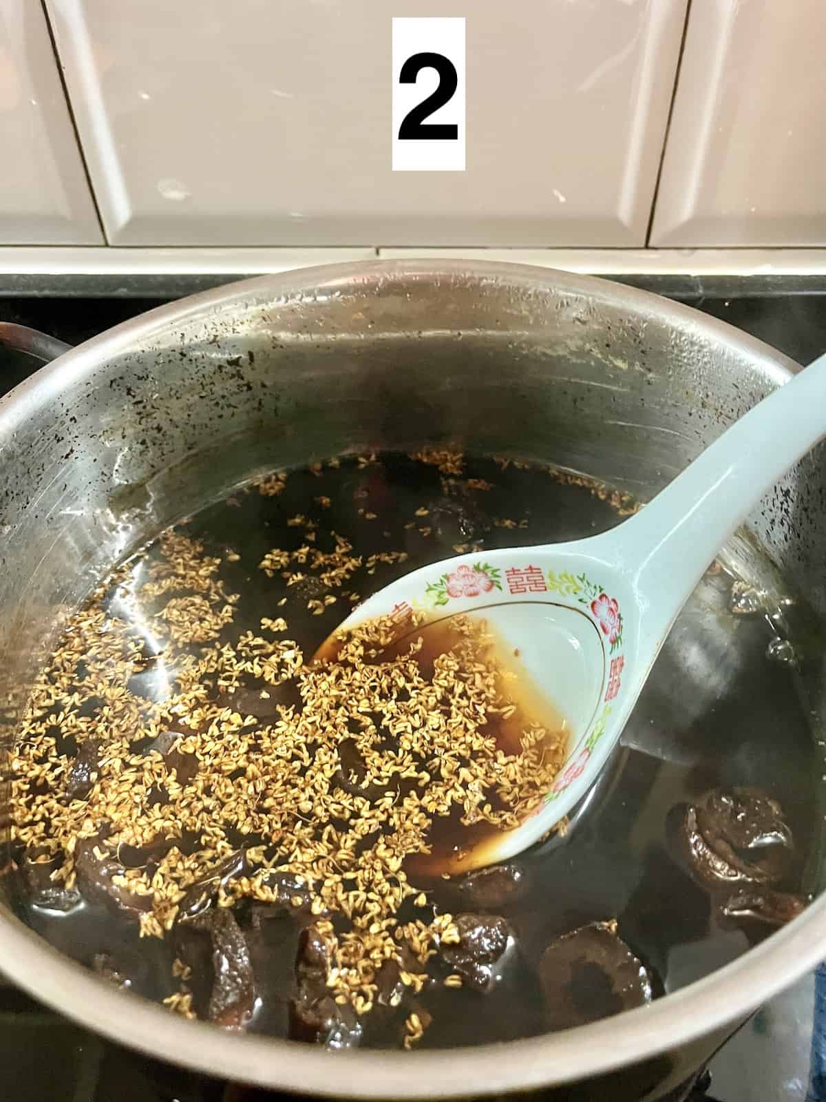 Stirring osmanthus sugar into a simmering pot of chinese plum tea.