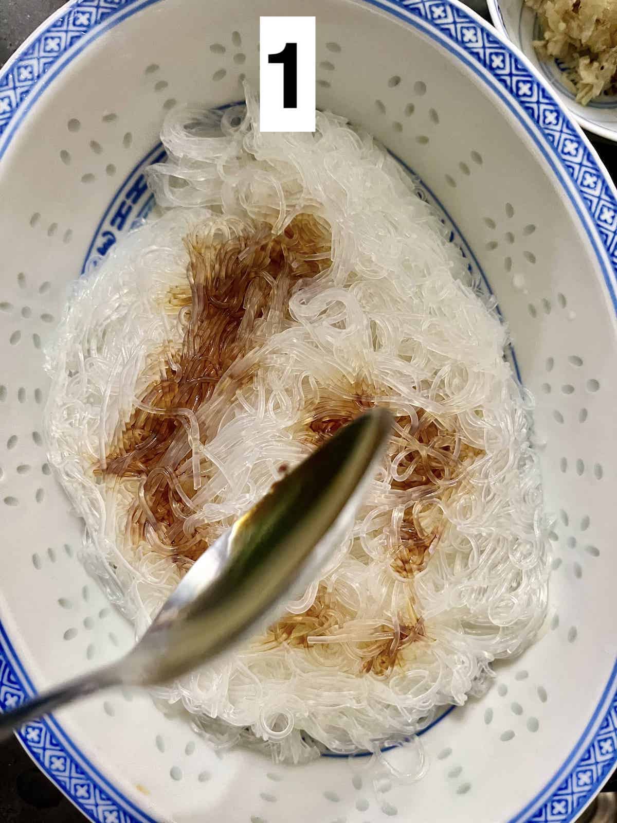 Pouring dark soy sauce onto Chinese noodles.