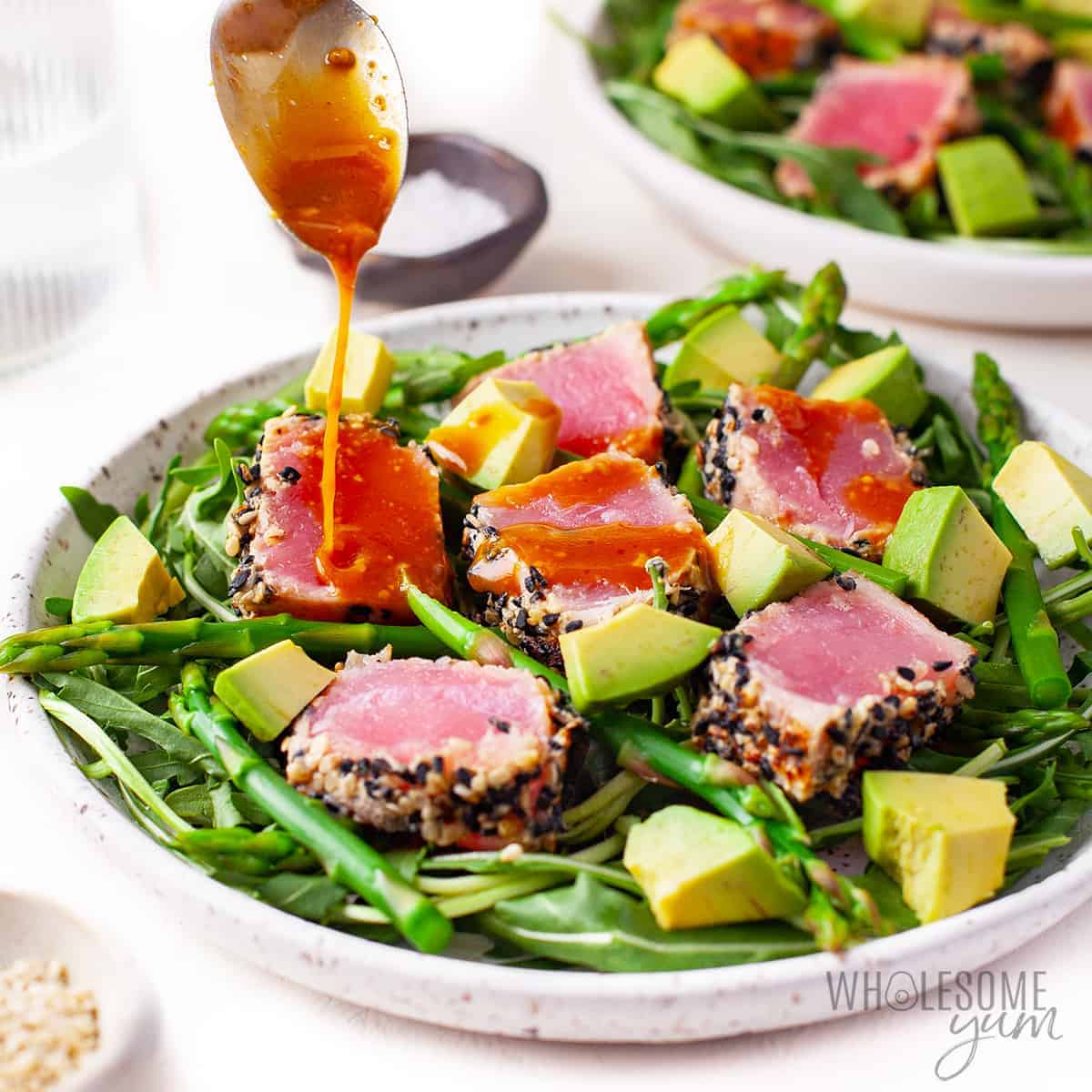 Drizzling dressing over black sesame crusted tuna and salad.