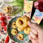 Close-up of a hand picking up a Chinese almond cookie.