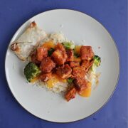 Firecracker tofu cubes on a white plate on a blue background.